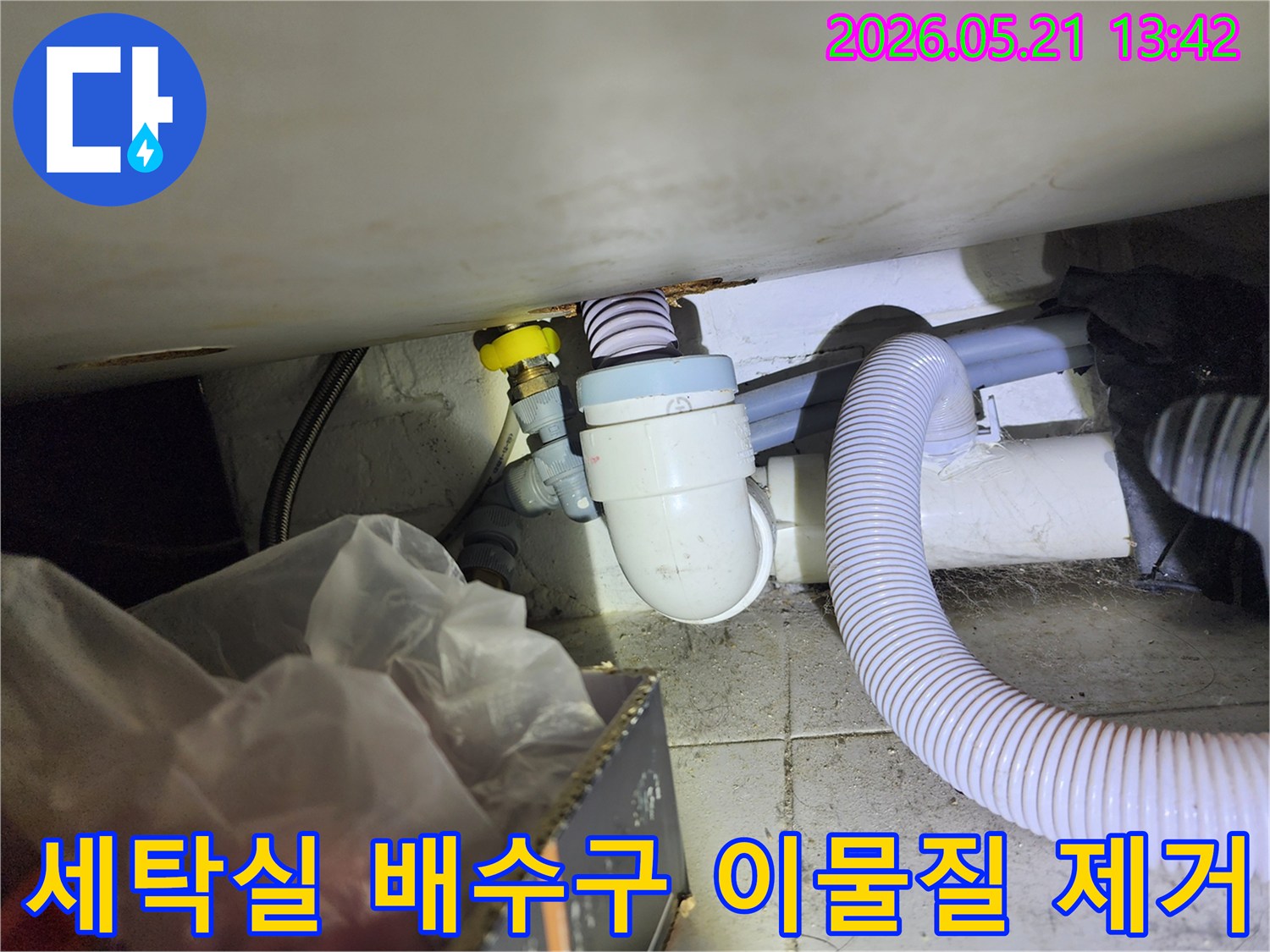 세탁실 배수구에 쌓인 이물질을 제거하여-막힘 문제를 해결하는 작업 현장입니다.