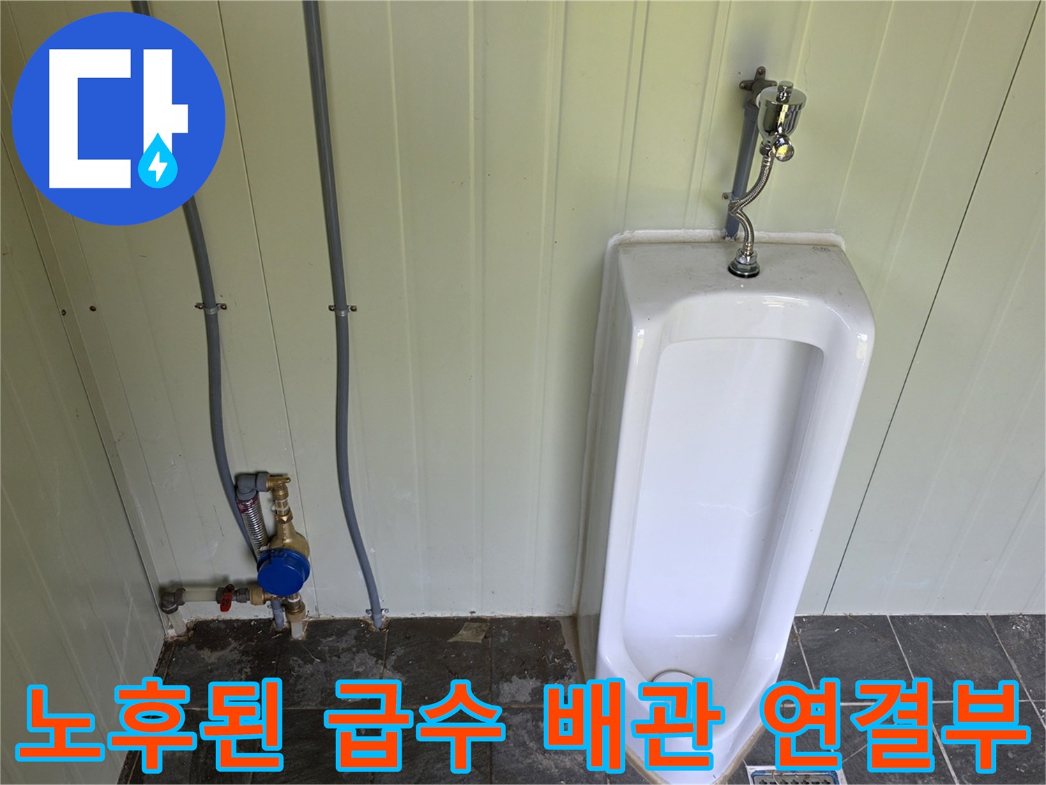 소변기 뒤쪽 벽면의 급수용 은색 파이프와 계량기