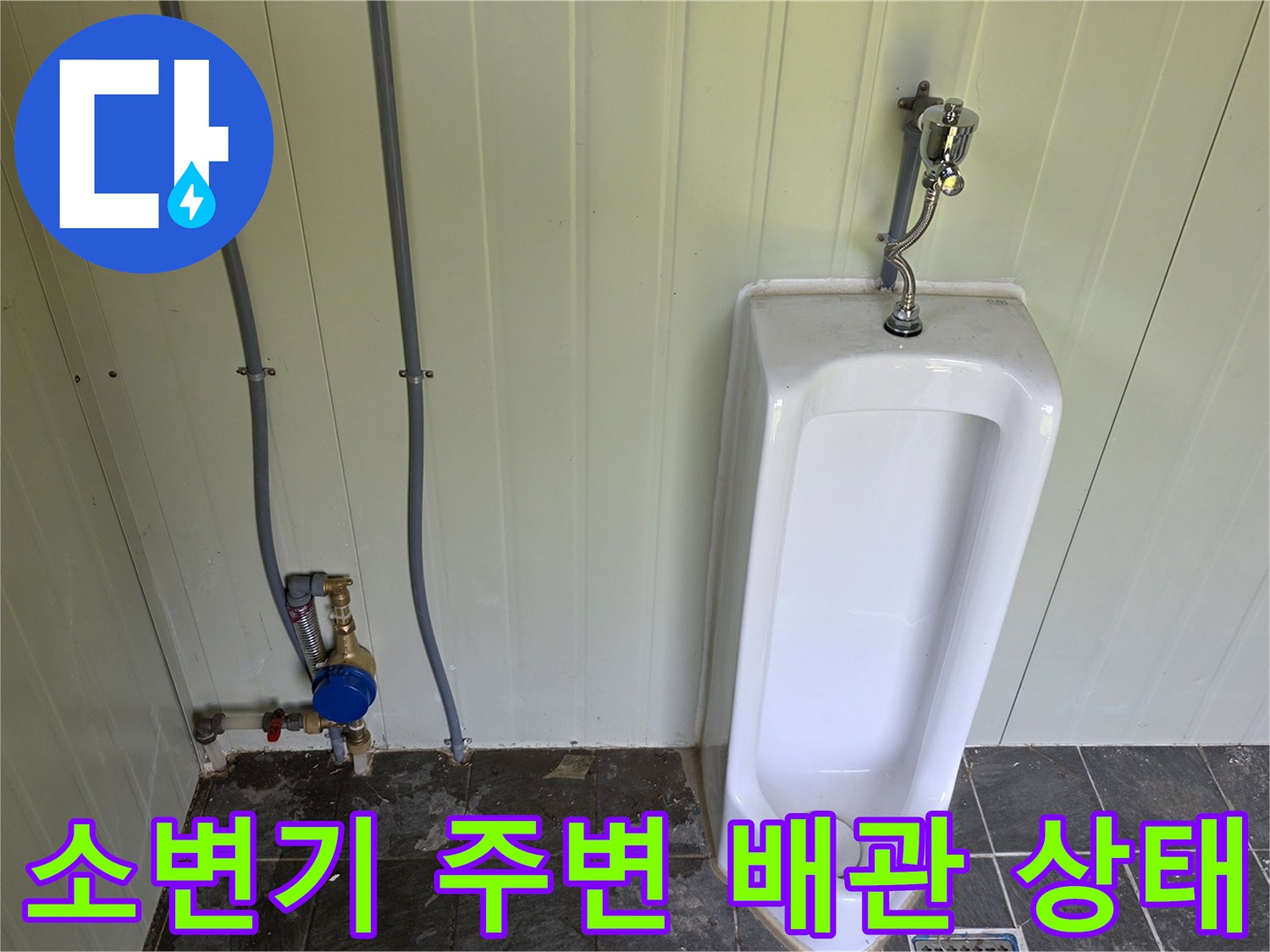 소변기 옆 수도 계량기와 급수 배관의 모습입니다.