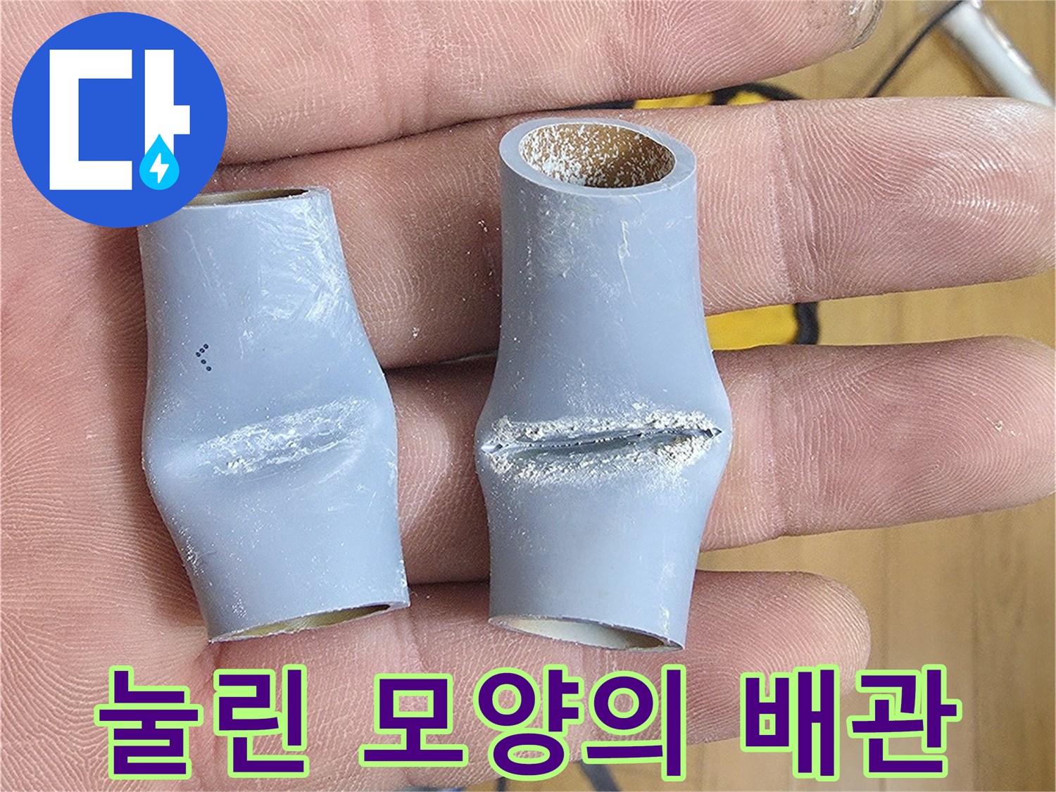 손가락 사이에 끼워진 변형된 회색 배관 부속