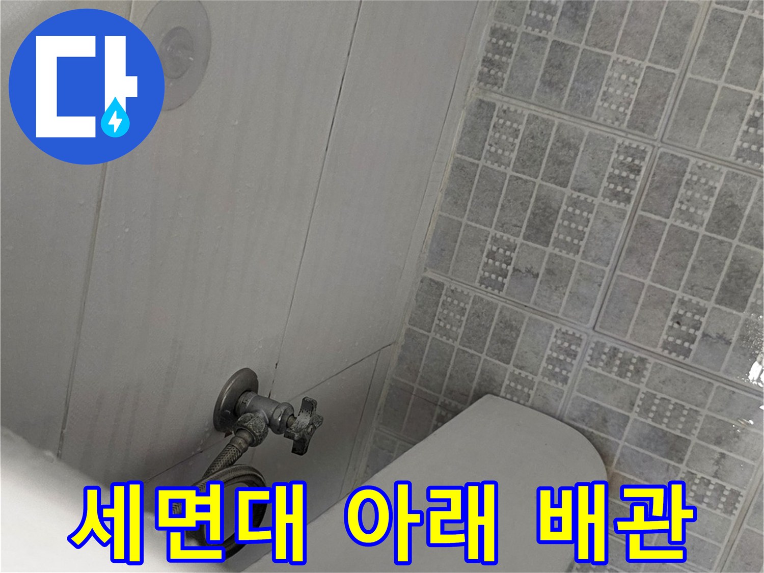 세면대 하단 수도 연결 부위와 타일 바닥 모습
