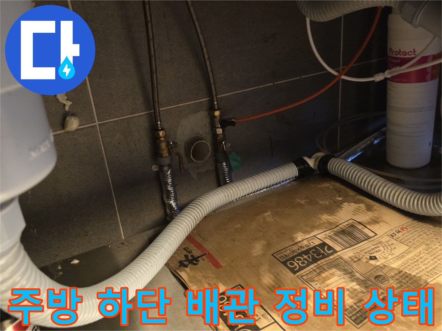 식당 주방 하부의 복잡한 냉온수 배관과 연결 호스 점검 모습