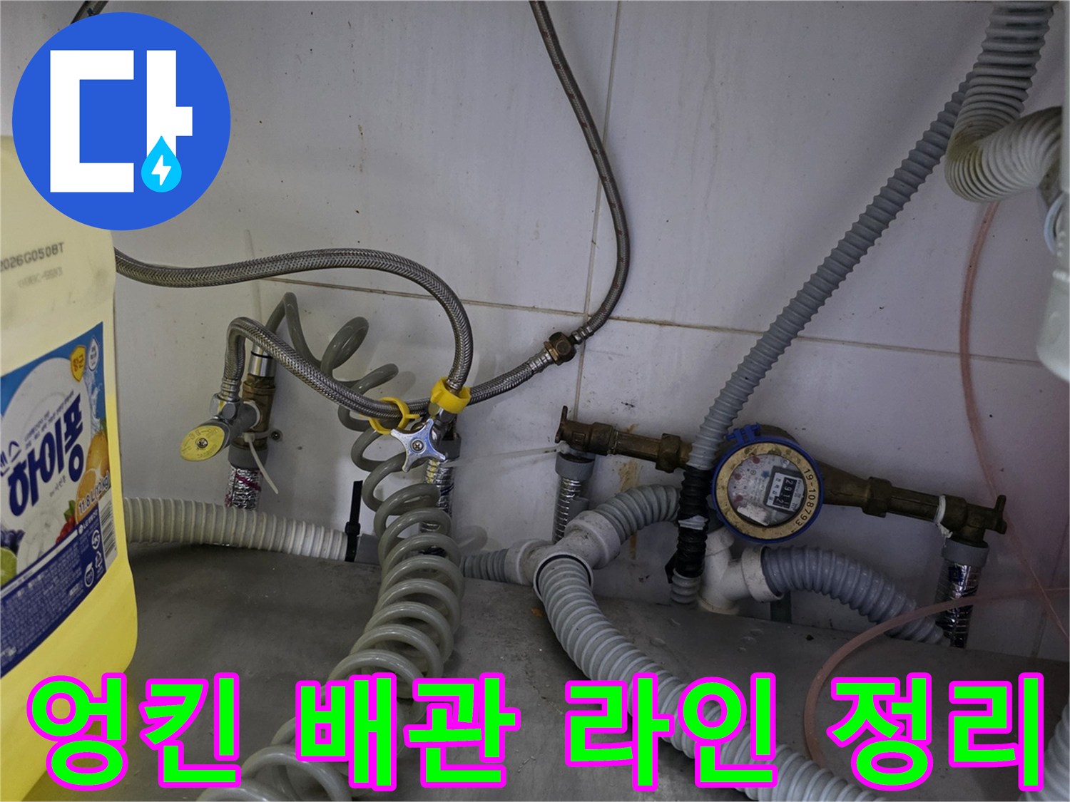 주방 하단 설비-복잡하게 얽힌 수도 호스와 계량기 장치