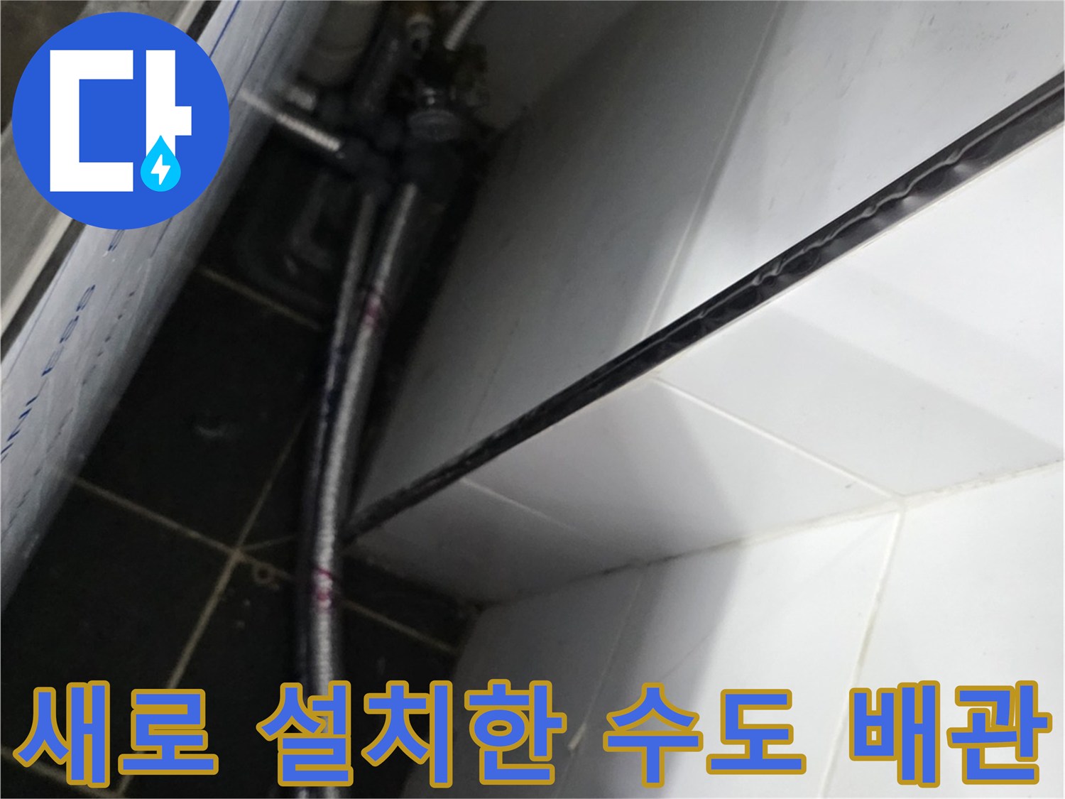타일 벽면 하단에 고정된 은색 금속 재질의 신설 배관