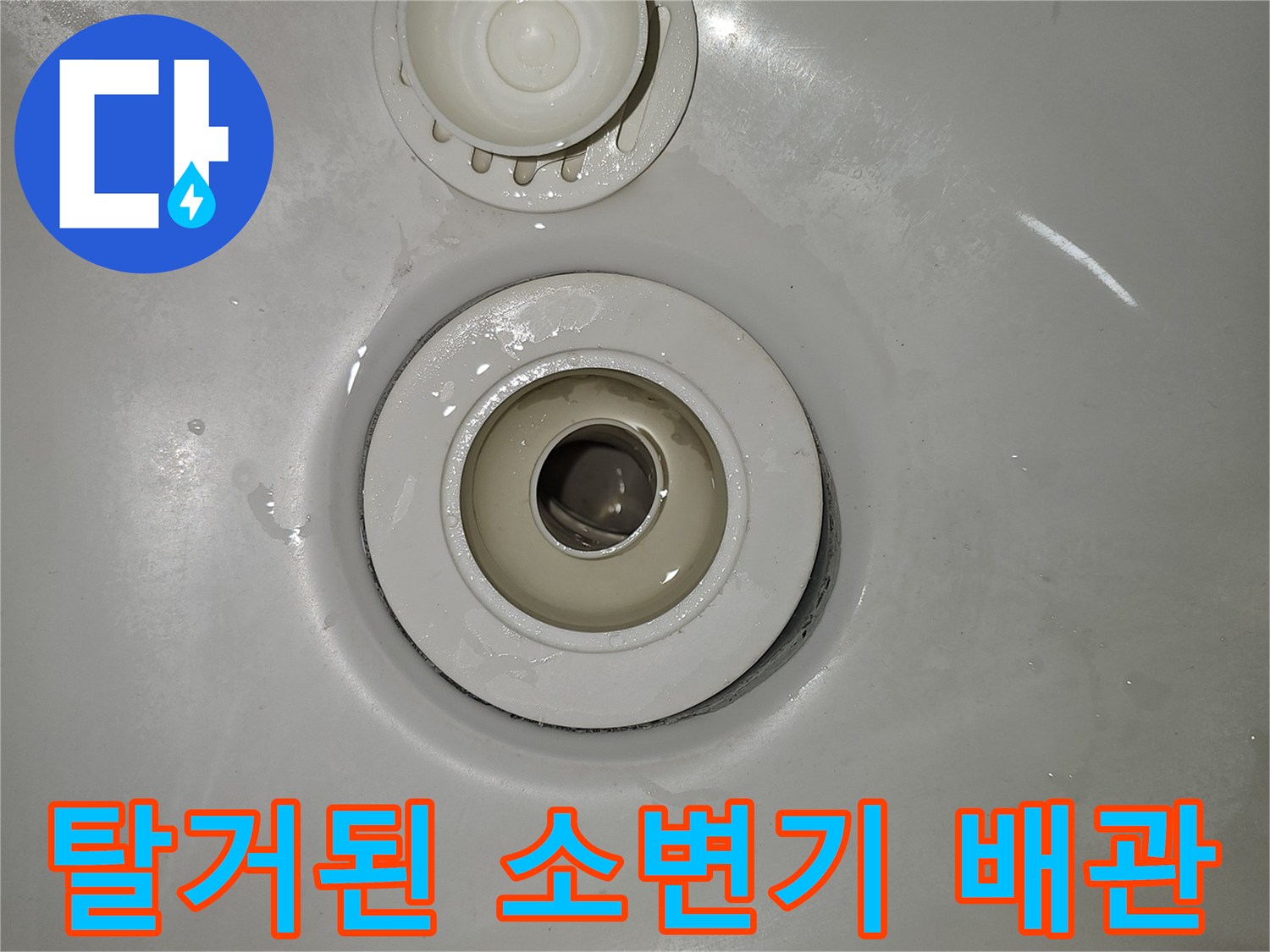 소변기 하단에 노출된 배관과 덮개 부속품의 모습