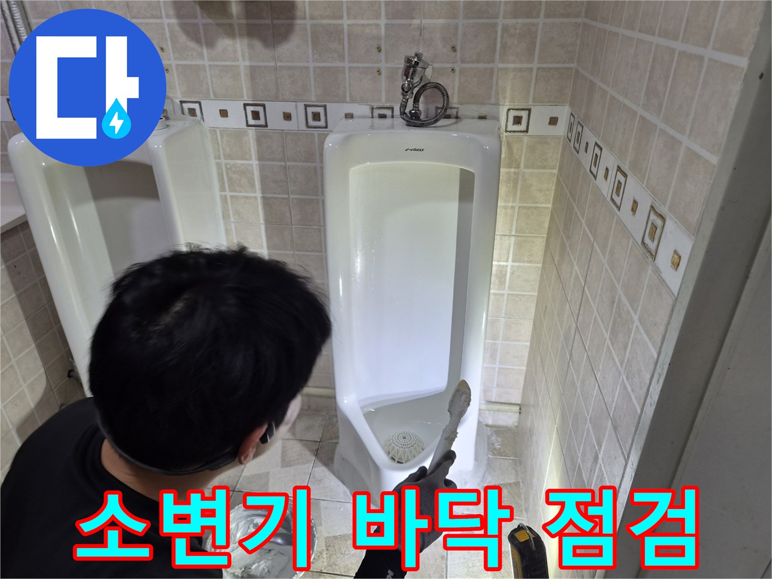 소변기 하부의 배관 연결 부위와 타일 틈새를 점검하는 작업 장면입니다.