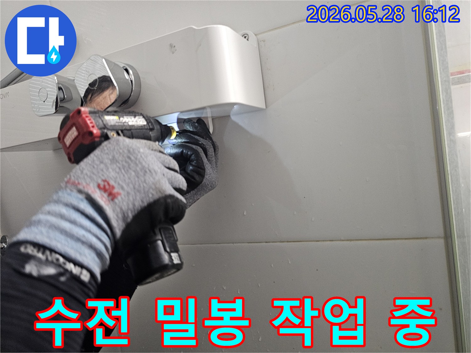 전문 기술자가-보호 장갑을 착용하고-전동 공구로-샤워기 수전의-누수 부위를-정밀하게-밀봉하는-작업 현장입니다