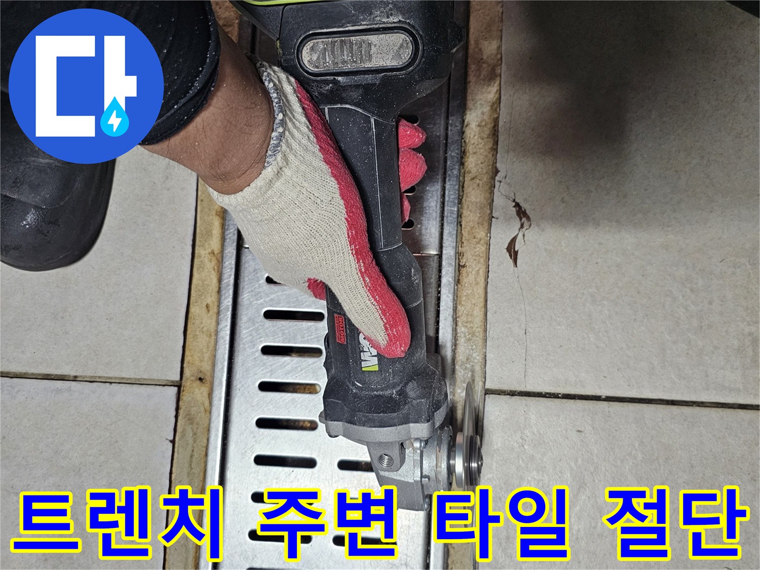 그라인더를 사용하여 트렌치 덮개 주변 타일을 제거하는 작업자
