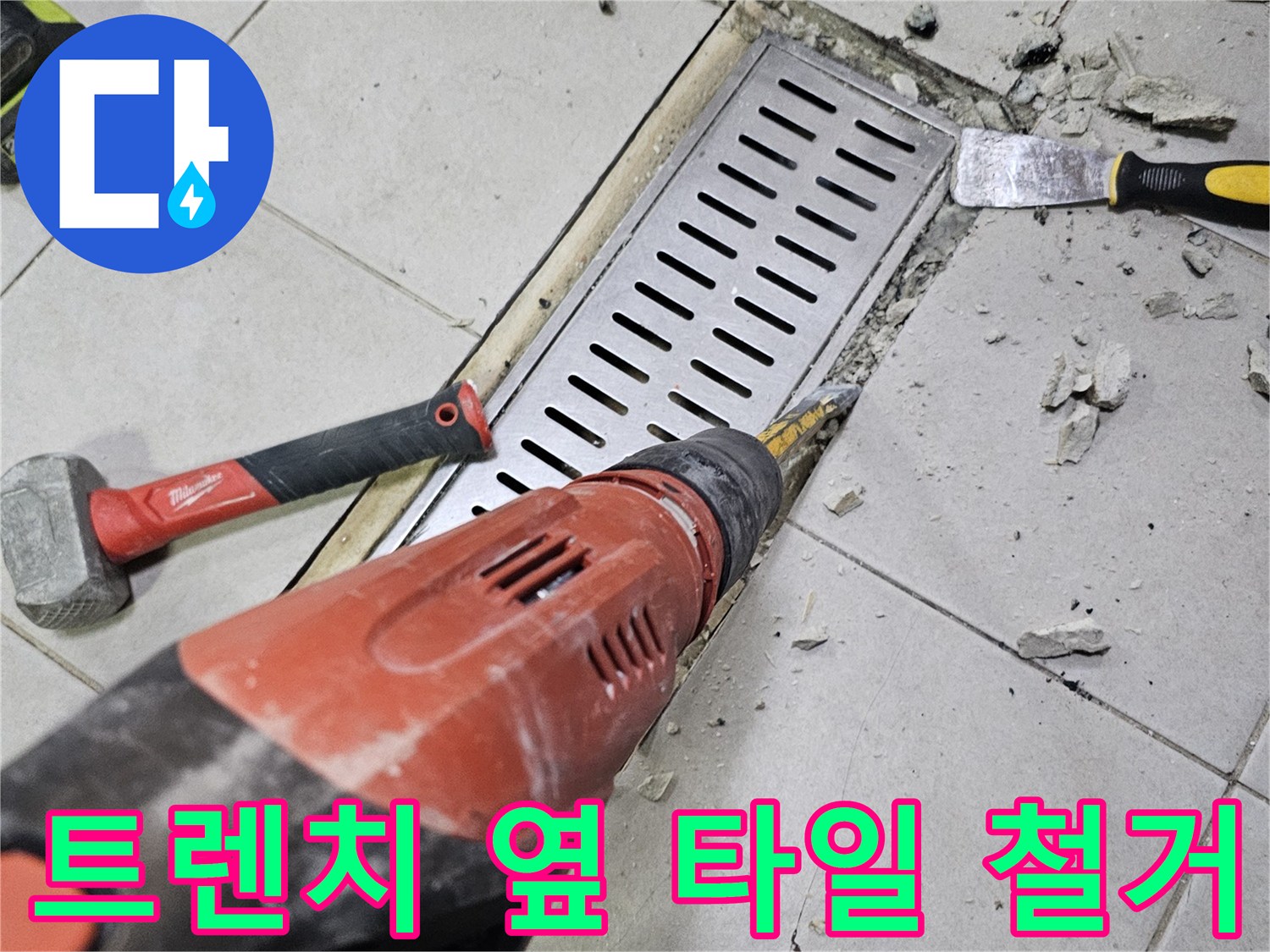 금속 트렌치 덮개와 주변 타일을 분리하는 작업 장면