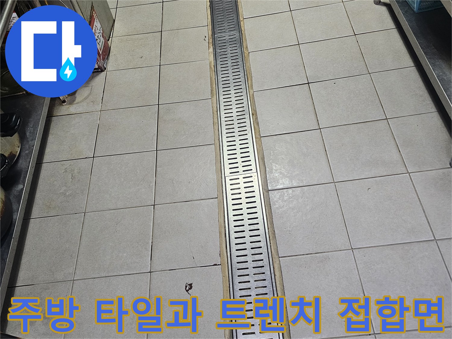긴 스테인리스 배수구와 주변 타일 바닥의 경계 부위