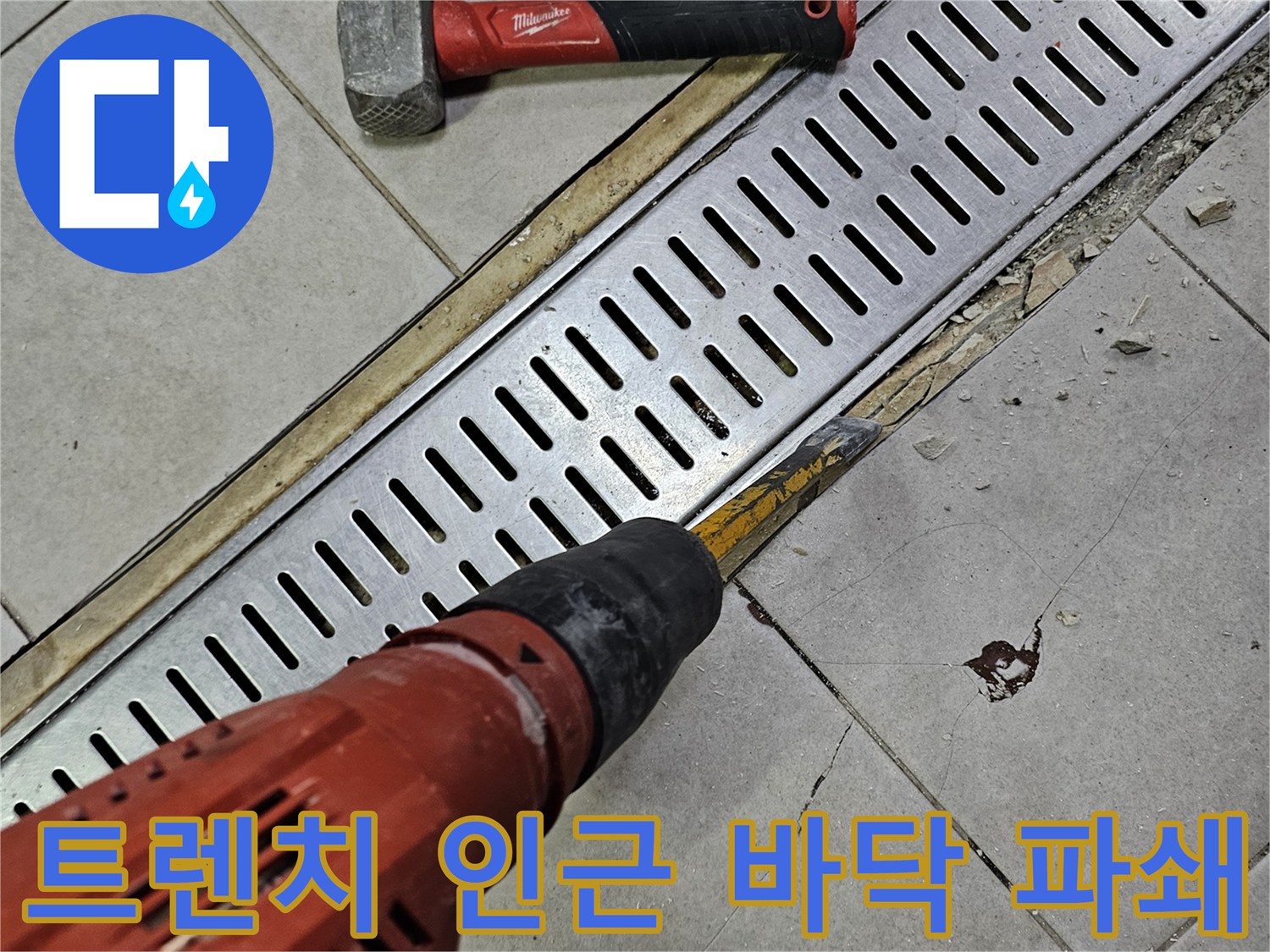 망치와 드릴을 사용하여 트렌치 주변 타일을 뜯어내는 모습