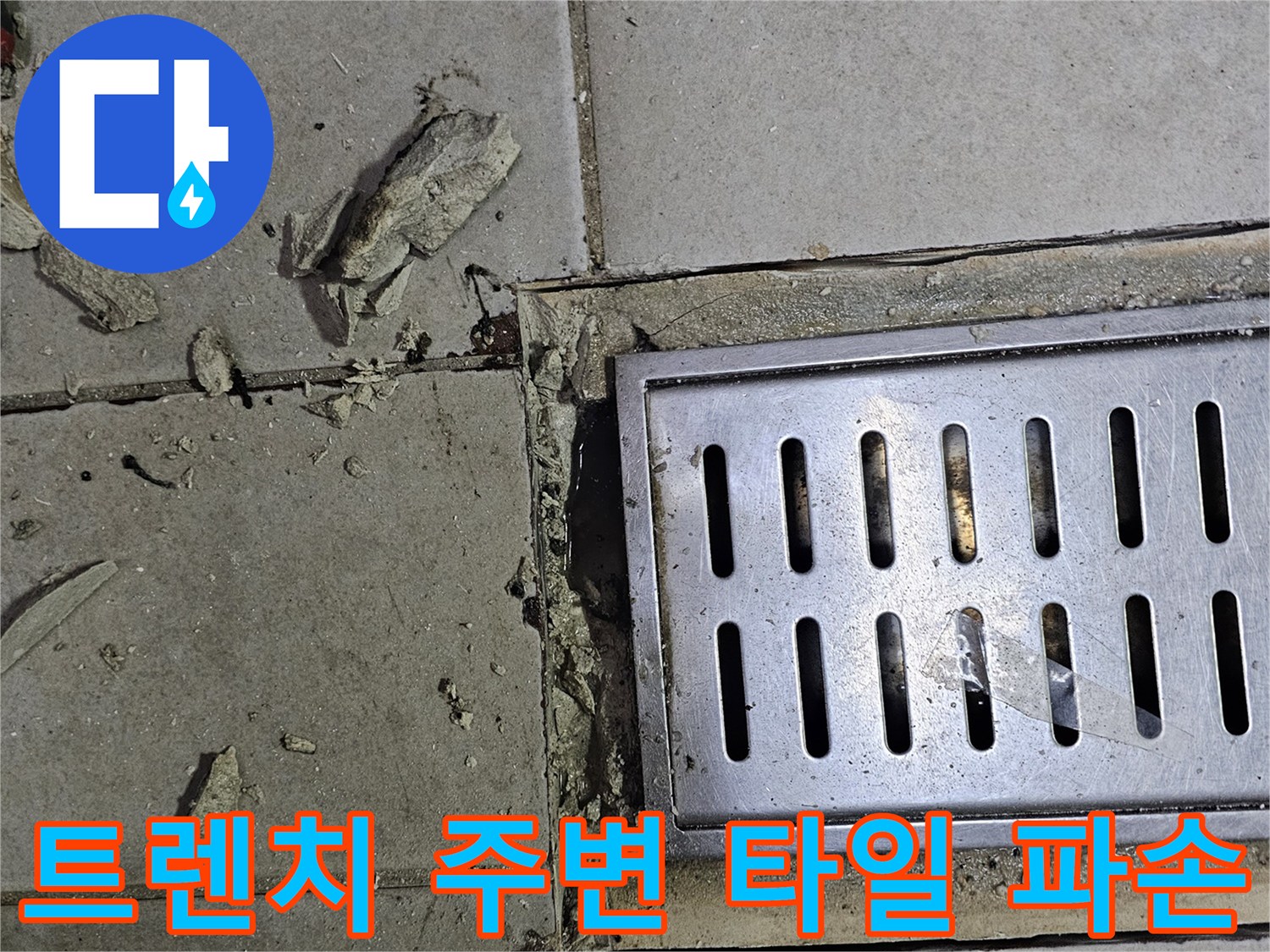배수 트렌치 덮개 근처의 깨진 타일과 시멘트 가루 상태