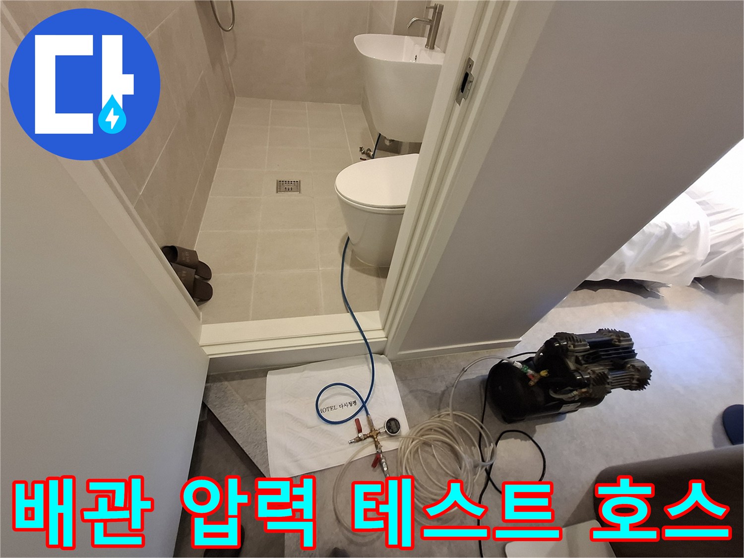 욕실 바닥에서 진행 중인 배관 압력 체크용 호스와 장비
