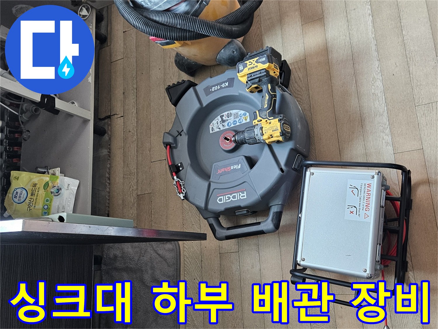 싱크대 하부장에서 사용 중인 배관 스케일링 장비와 석션기