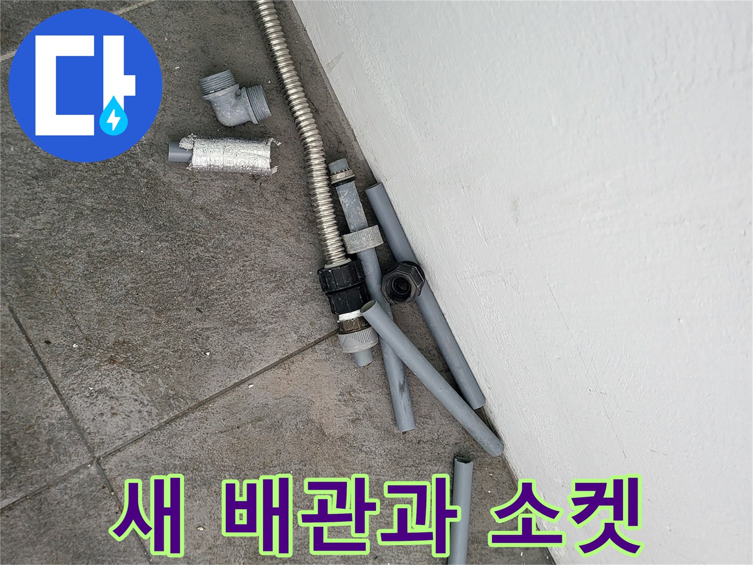 수리 작업 전 바닥에 놓여 있는 회색 배관 뭉치와 금속 부품