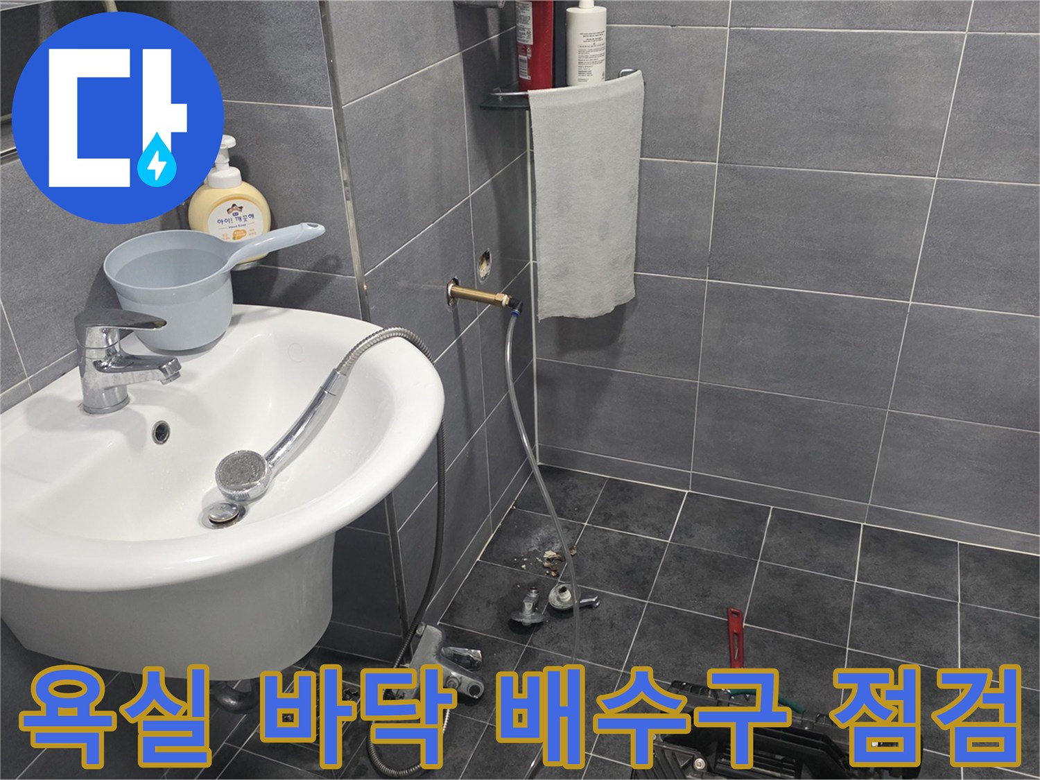 세면대 아래쪽 샤워기 수전과 타일 바닥의 배수구 부위
