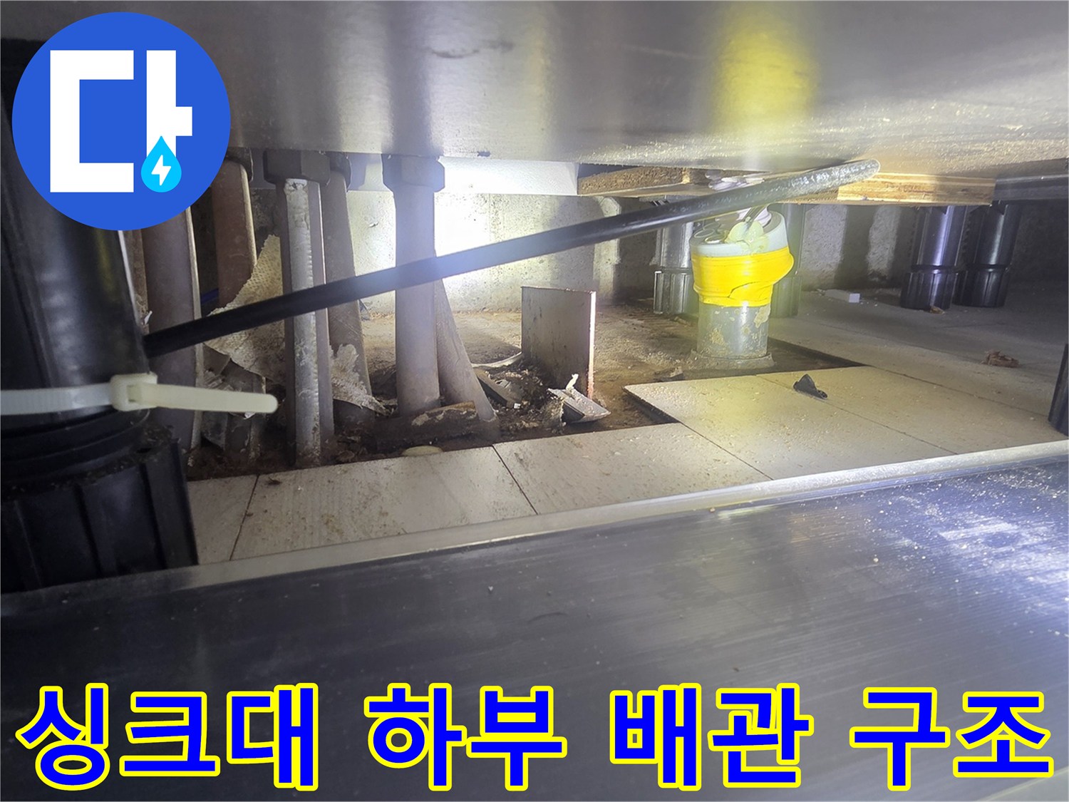 싱크대 아래 복잡하게 얽힌 배관과 연결 부품들의 상태 사진