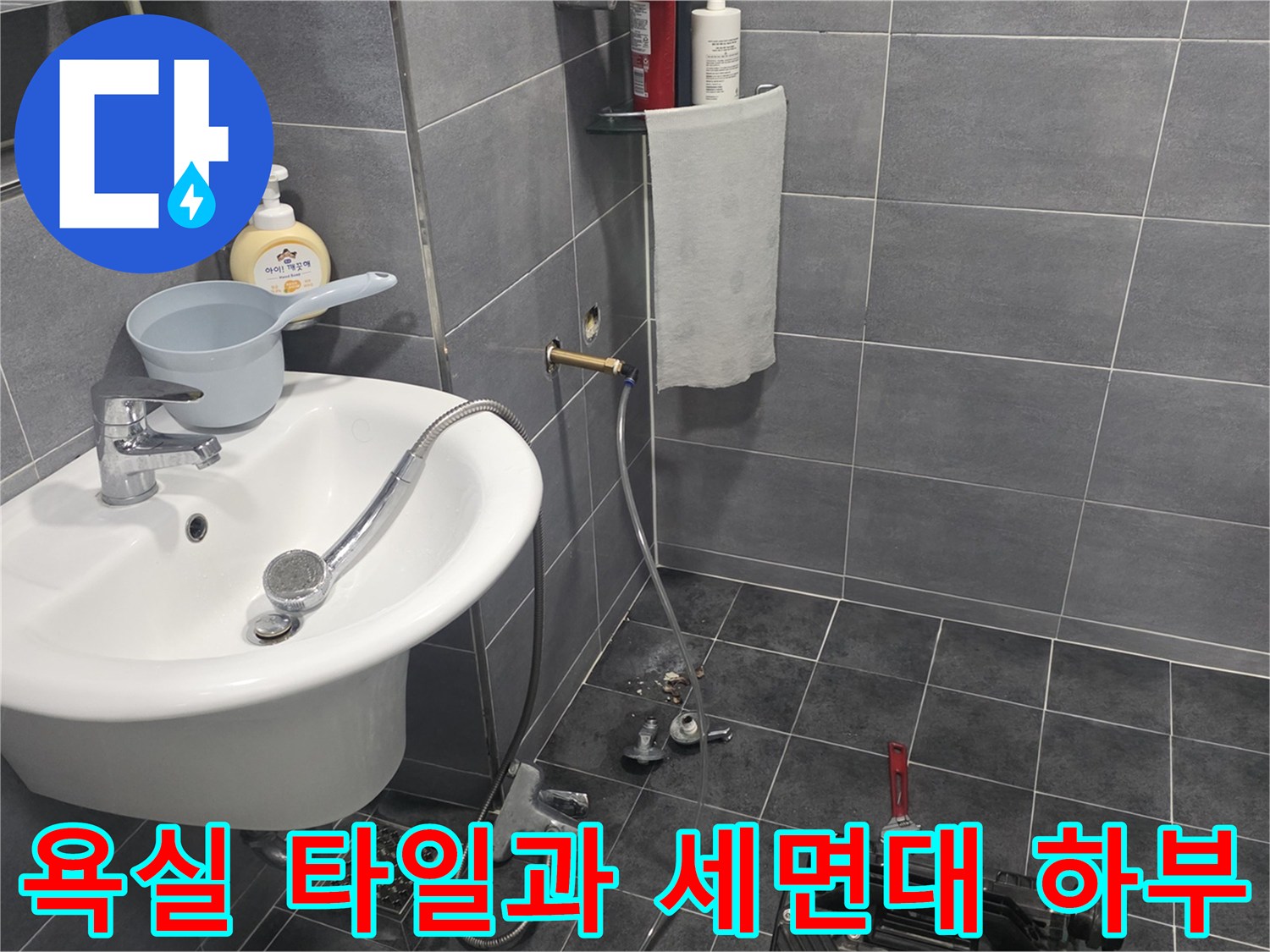회색 타일로 마감된 욕실의 세면대와 샤워기 시설 사진입니다.
