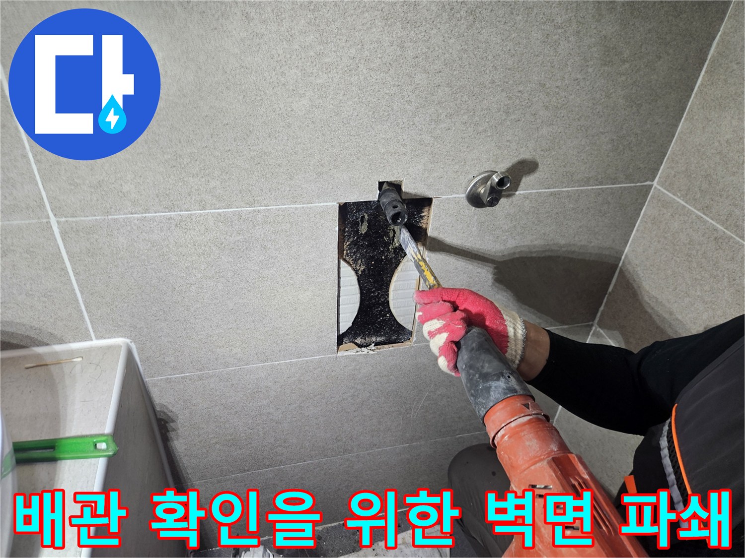 공구로 타일을 제거하여-매립된 수도관을 노출시키는 장면