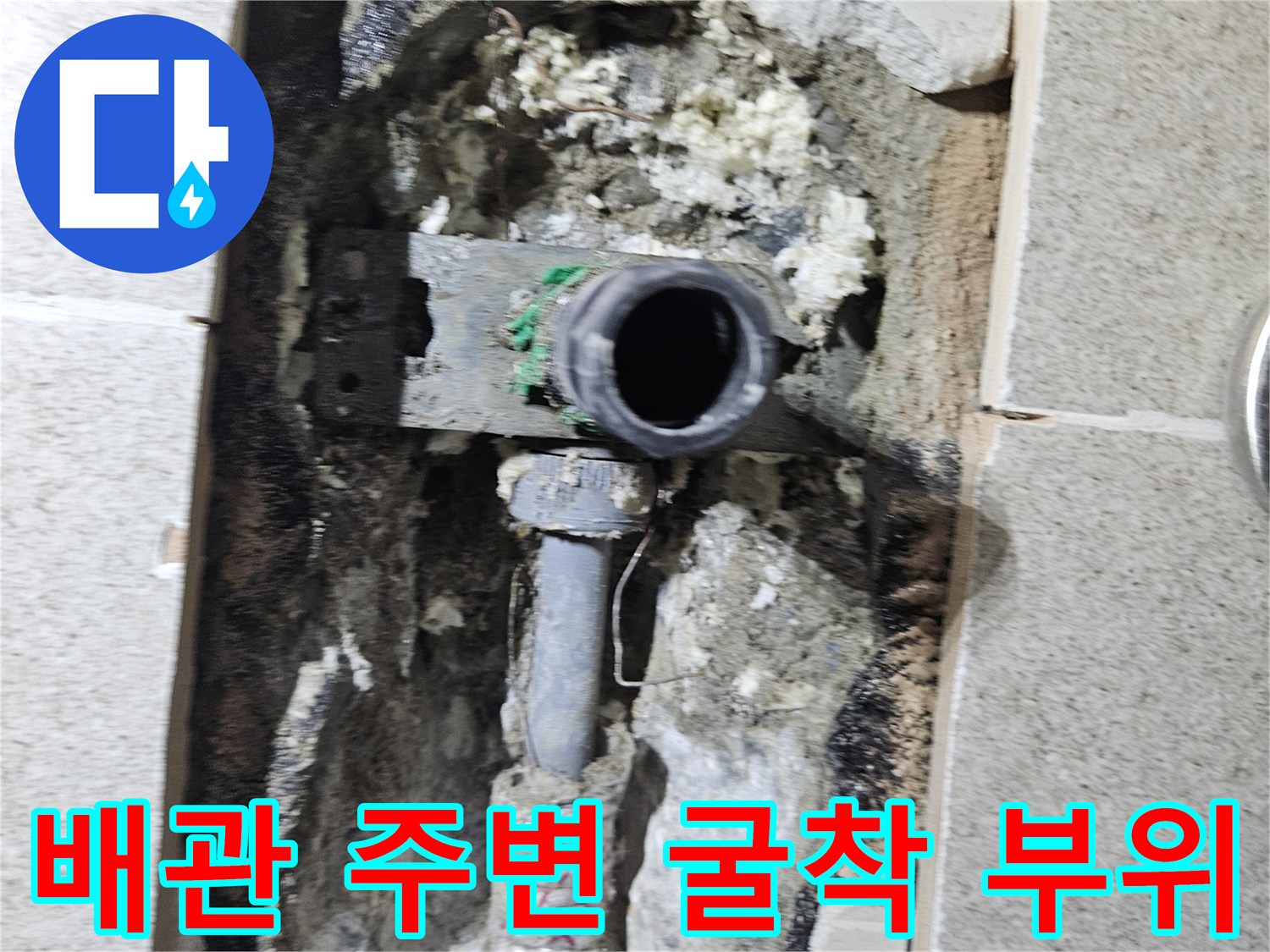 타일 아래 드러난 수도 배관과 젖은 벽체 내부