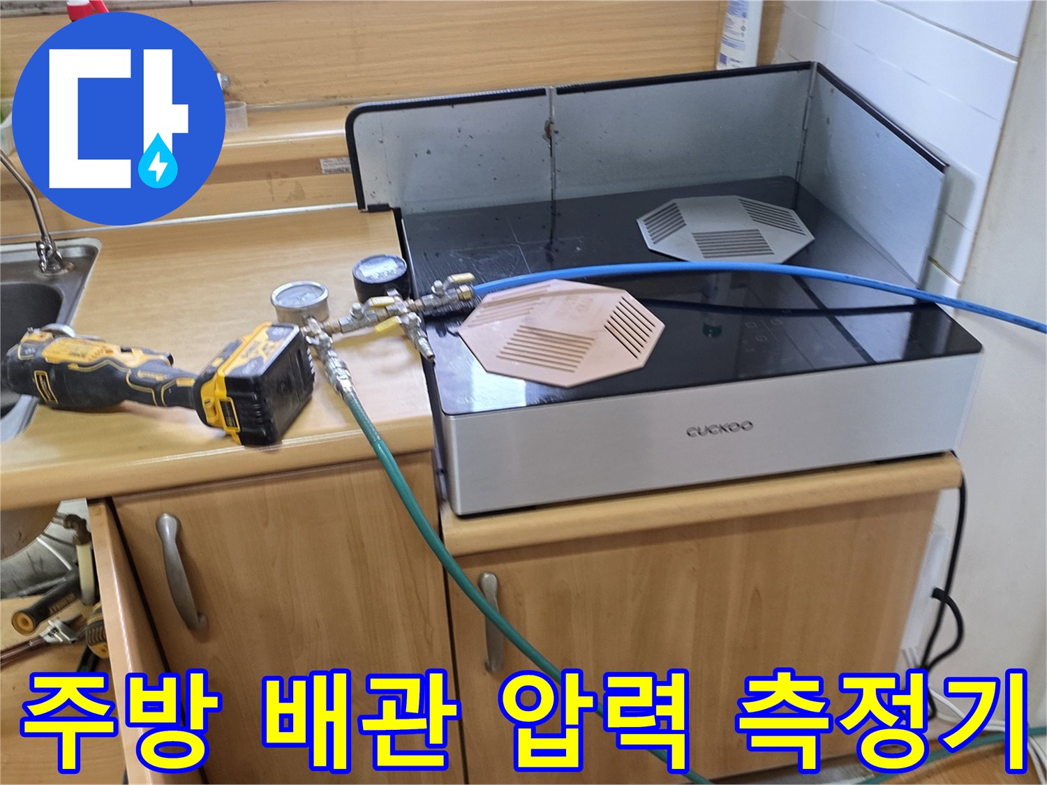 싱크대 아래 배관에 연결된 압력 게이지와 장비 모습