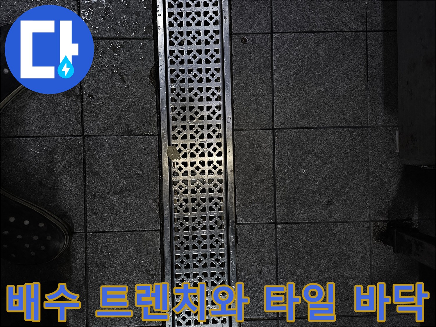 금속 재질의 배수구 트레이와 어두운색 사각형 타일 현장 사진
