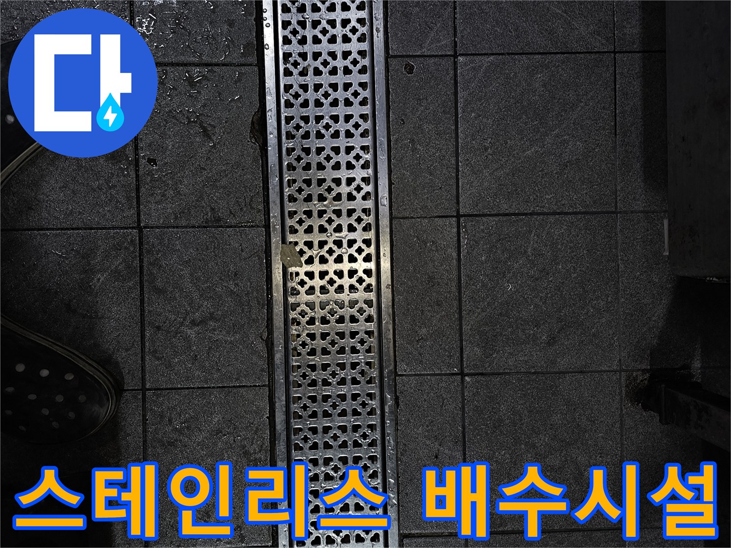 어두운 바닥 타일과 스테인리스 배수구의 모습