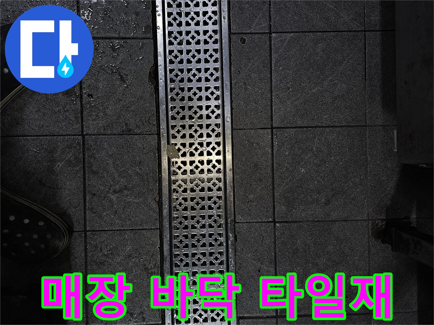 어두운 색상의 타일과 금속제 배수 트렌치 촬영