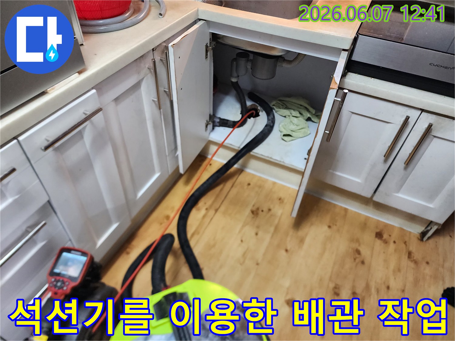 싱크대 하부 배관에 연결된 석션 호스와 작동 중인 장비입니다.
