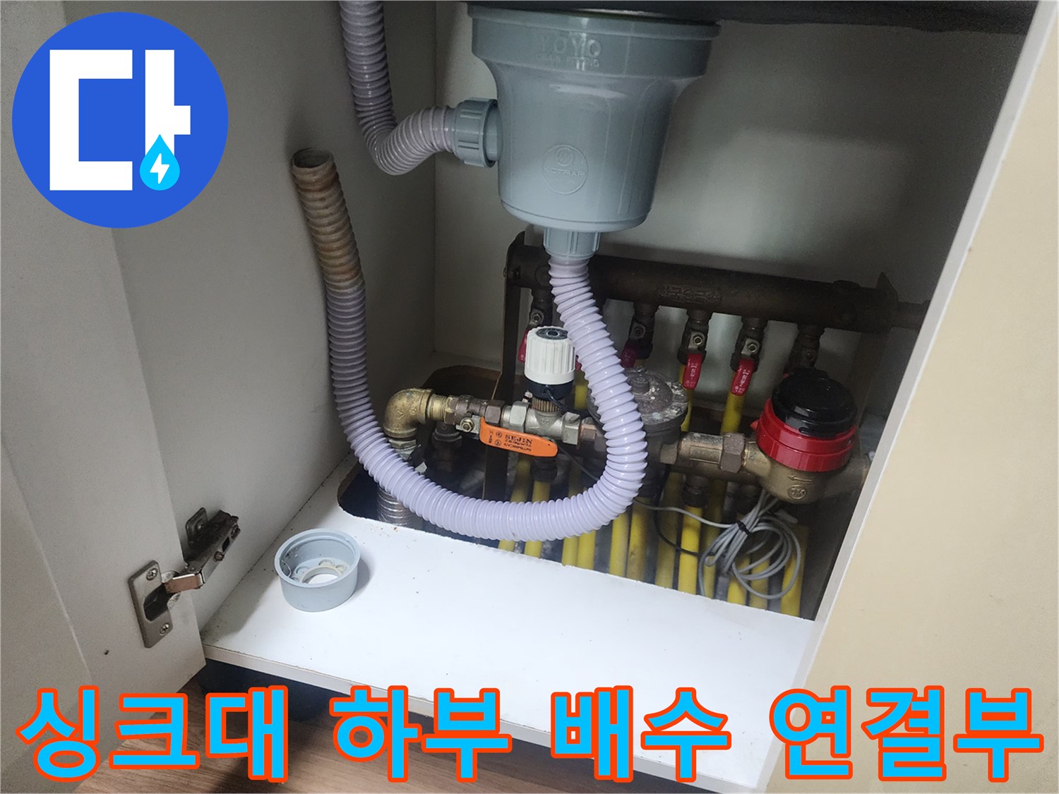 싱크대 밑바닥의 회색 트랩과 노란색 급수 밸브들의 배치 상태