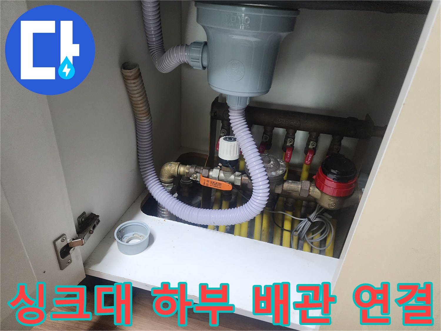 싱크대 아래 회색 주름관과 여러 갈래로 나뉜 배관들