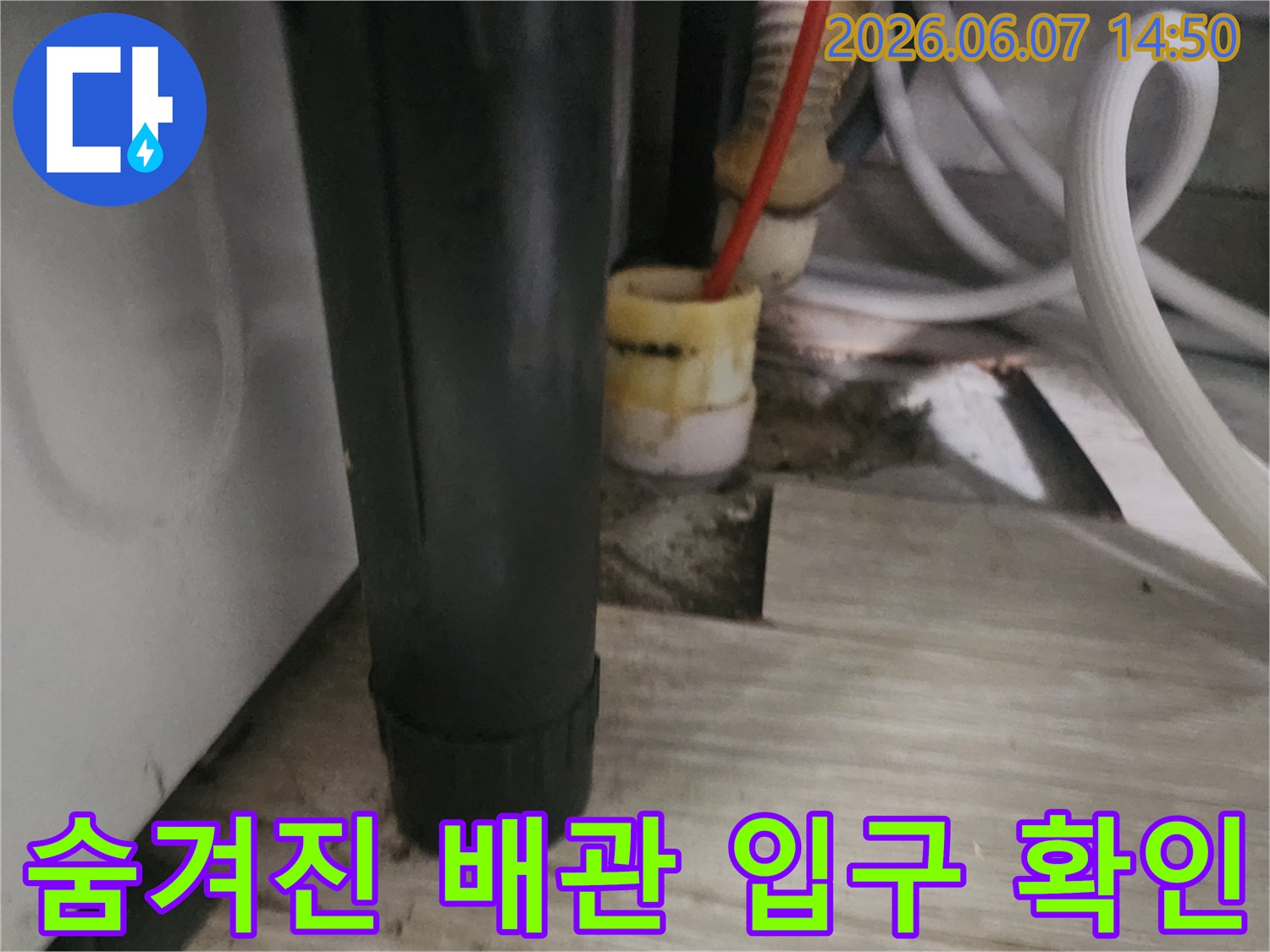 싱크대 하단부 - 장판 아래에 위치한 배수관 입구를 찾아 점검하는 장면입니다.