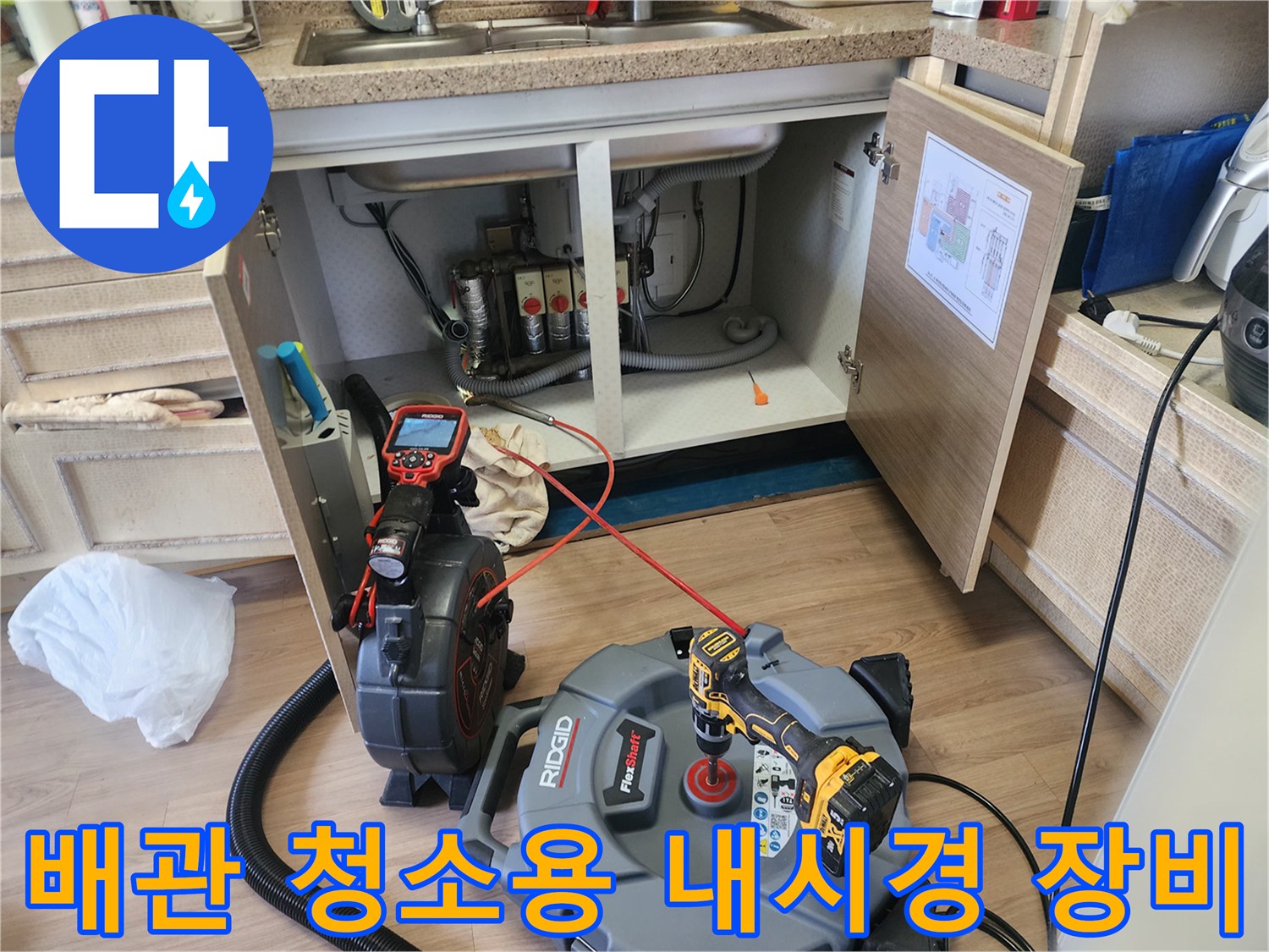 주방 싱크대 밑 배관 작업을 위해 설치된 전문 석션기와 내시관계 카메라