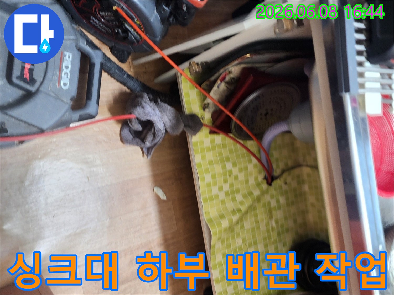 싱크대 하부 배관의 찌꺼기를 제거하기 위해 전문 장비를 가동하는 모습입니다.