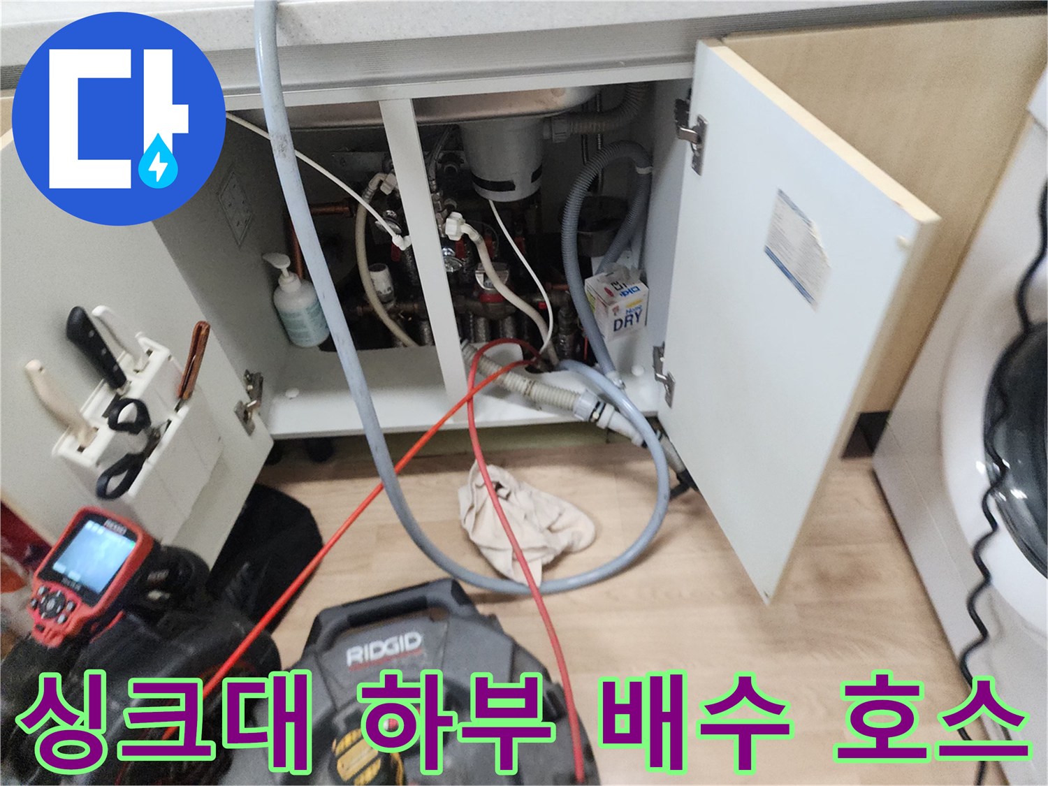 싱크대 밑바닥의 복잡한 배수 호스와 작업용 장비 모니터