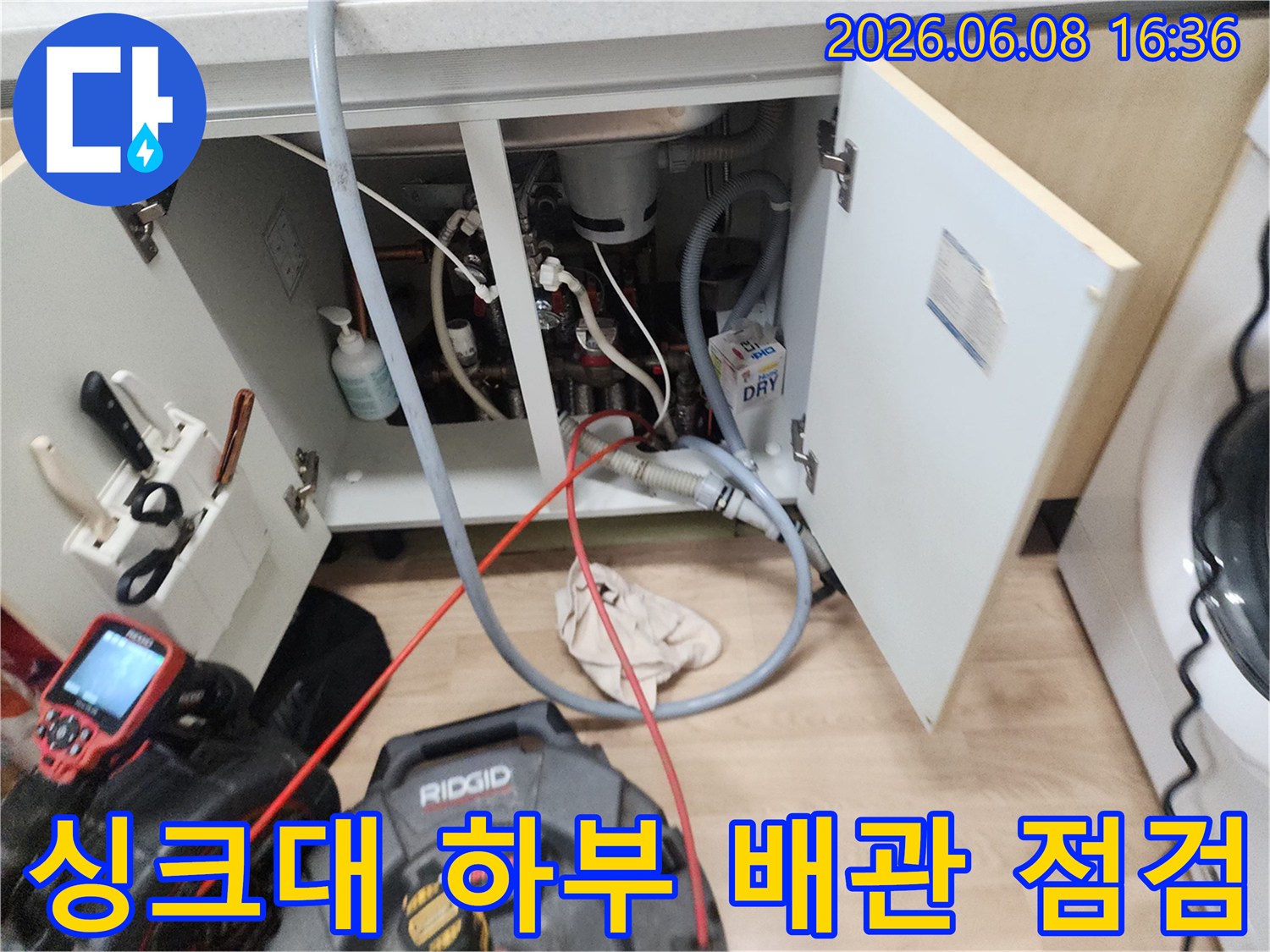 싱크대 아래쪽 복잡한 배관과 작업용 장비가 배치된 모습입니다.