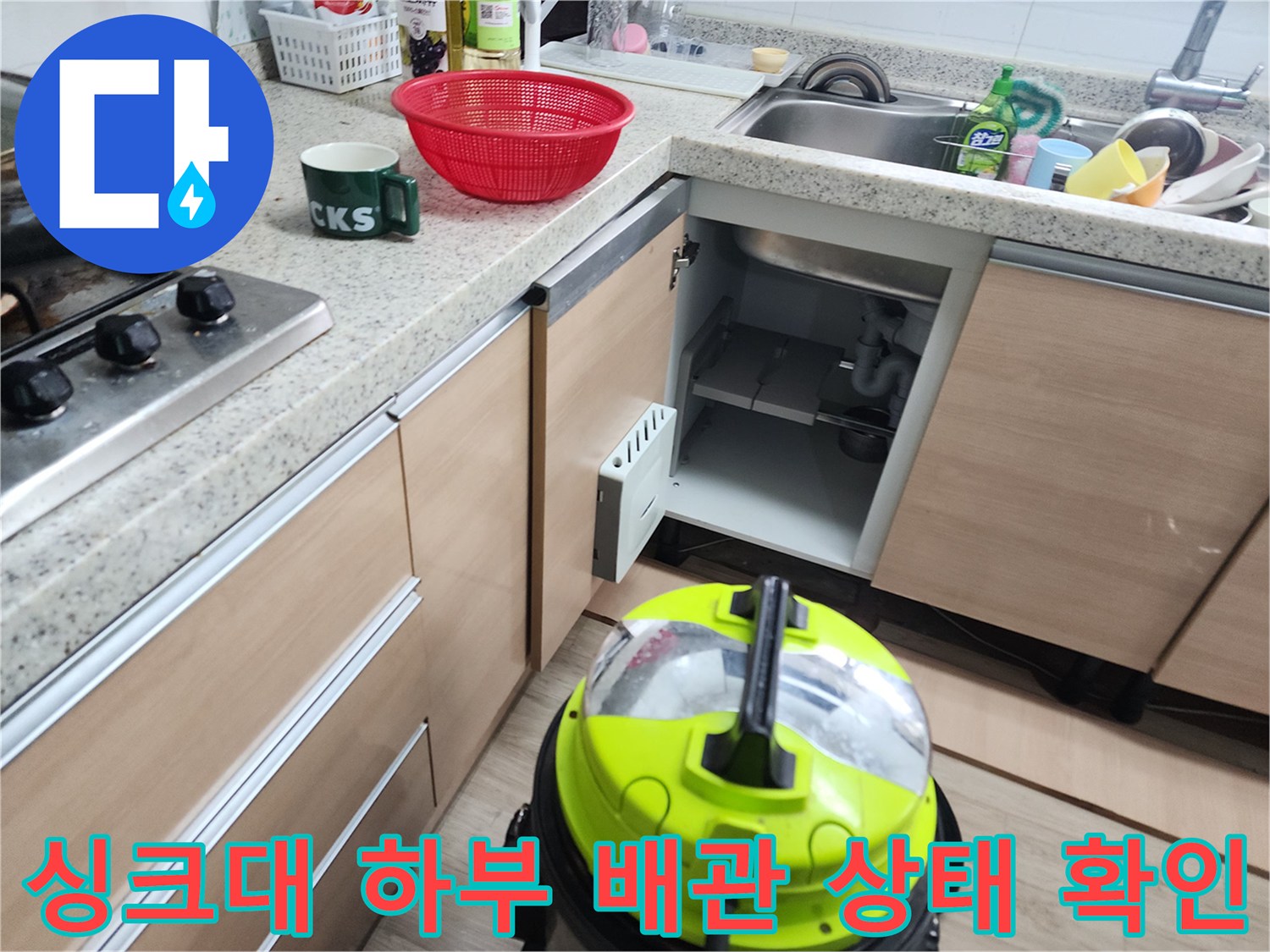 열려 있는 싱크대 하부장과 노출된 배수 파이프 라인