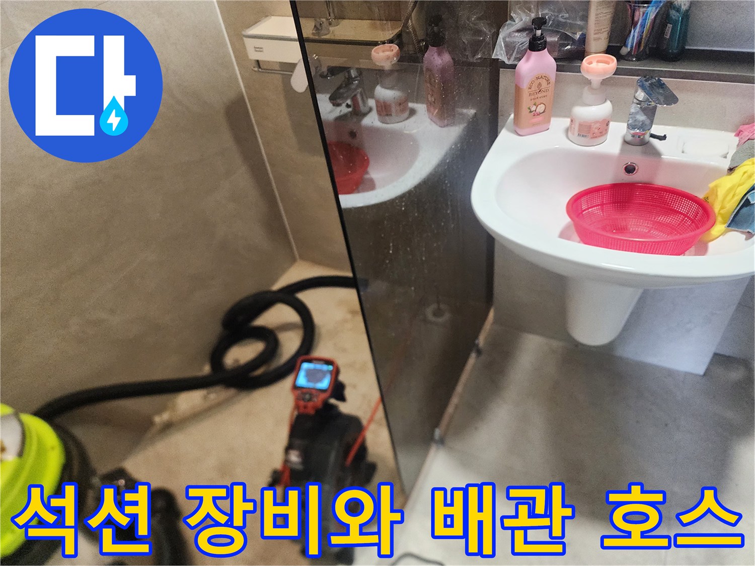 화장실 바닥에 놓인 배관 청소용 석션기와 연결된 검은색 호스