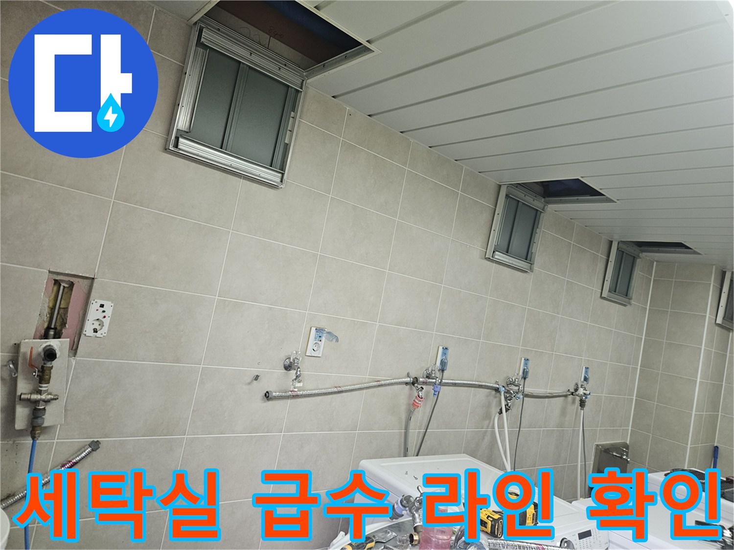 조종면 세탁실 벽면-노출된 급수 배관과 타일 마감 상태