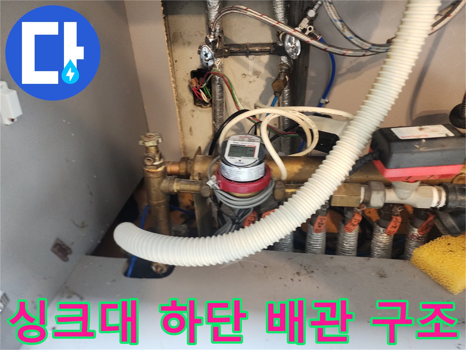 주방 싱크대 밑 수도 계량기와 연결된 금속 배관 상세 사진