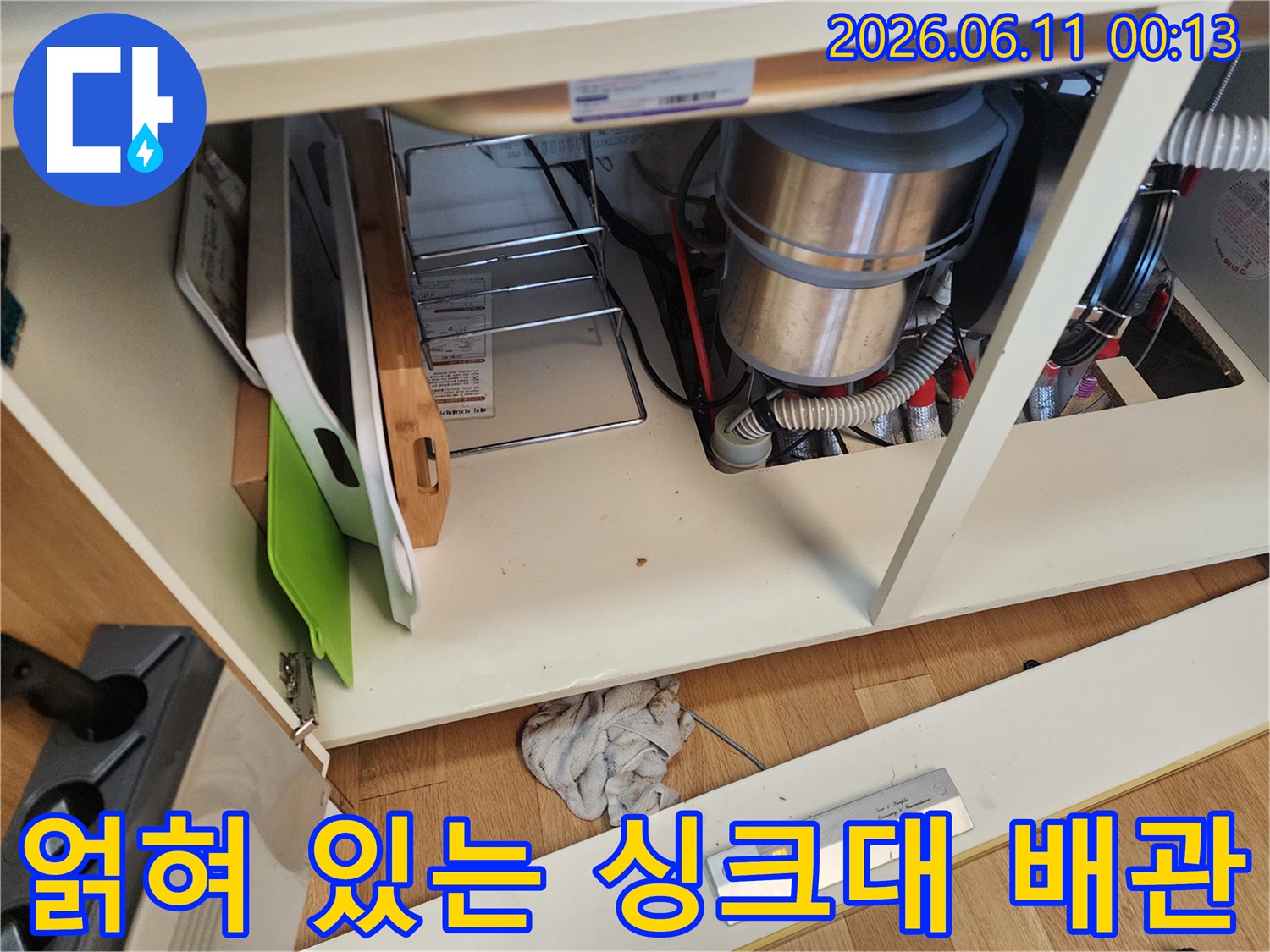 싱크대 하단부의 복잡한 배수 호스와 연결 부위 근접 촬영