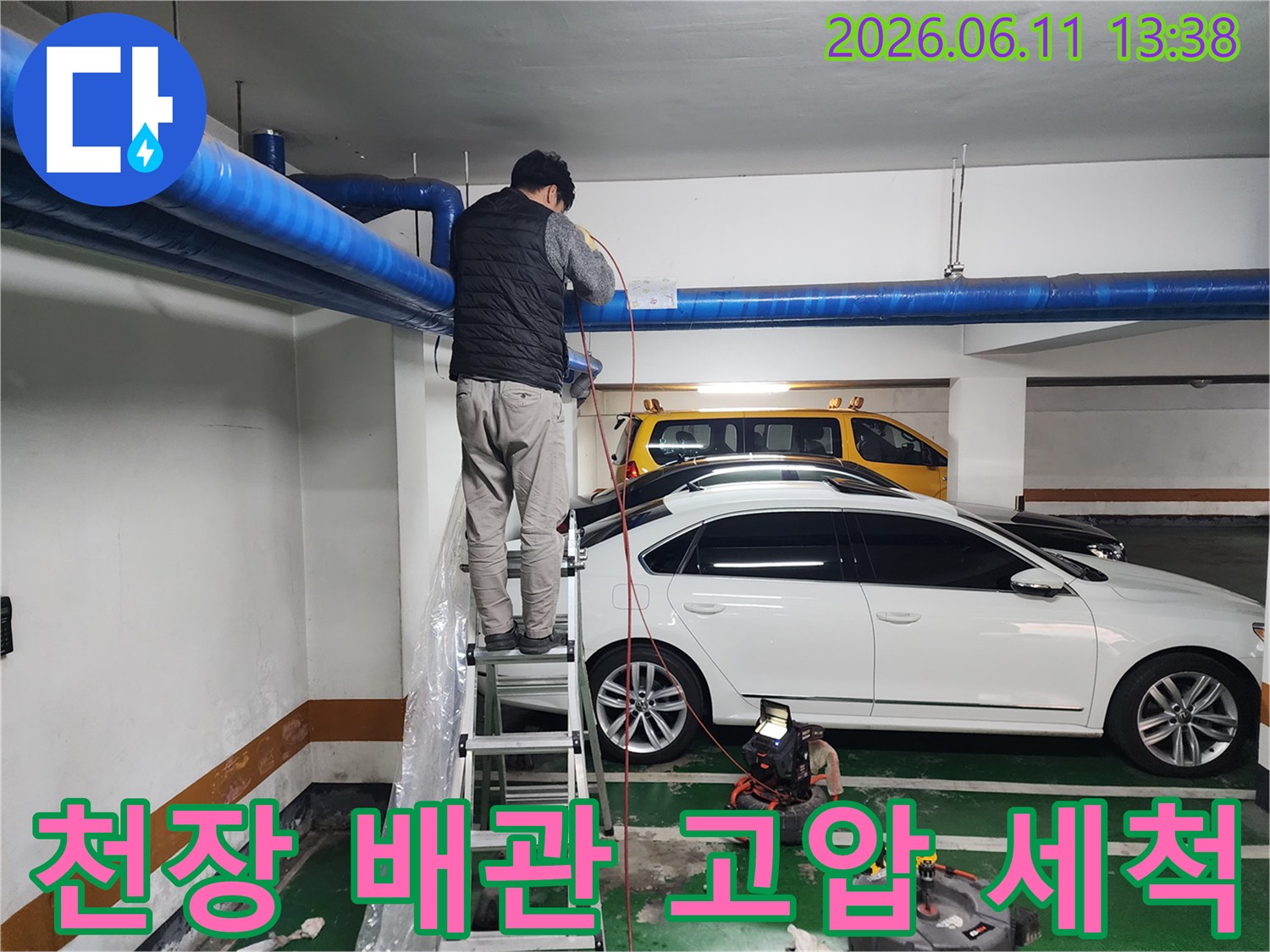 사다리 위에서 파란색 대형 배관을 점검하는 작업자 모습