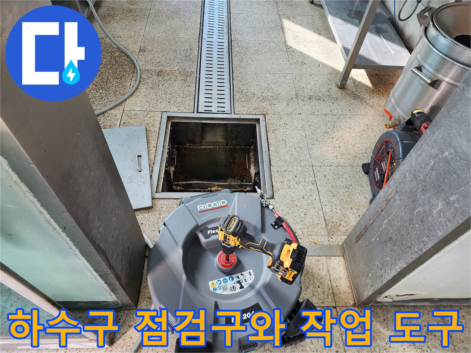트렌치 아래 점검구 주변에 놓인 배관 청소용 장비 세트