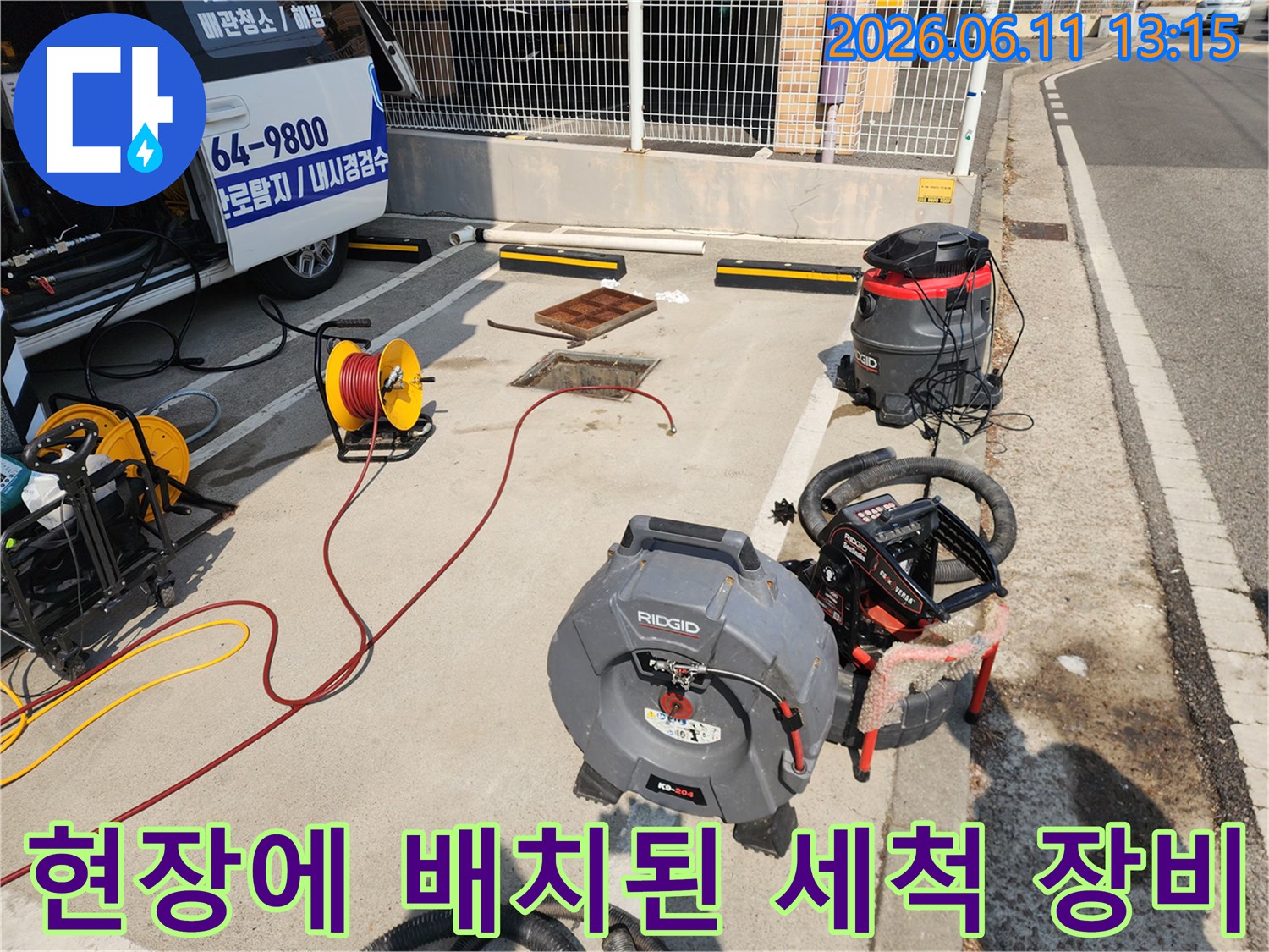 맨홀 덮개 근처에 놓인 고압 세척기와 호스 연결 상태