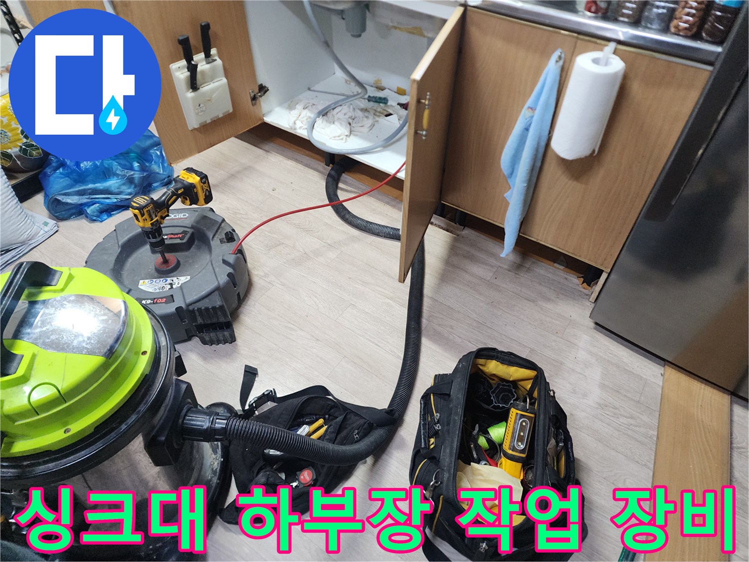 싱크대 하부장 바닥에 배치된 석션기와 배관 청소용 전문 장비들