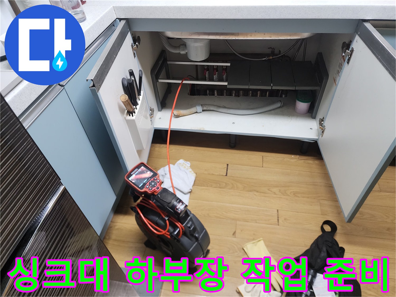 작업을 위해 개방된 싱크대 하부장과 전문 장비들