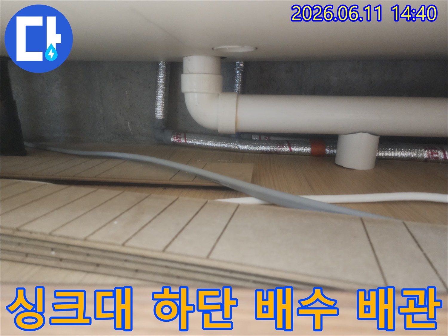 싱크대 밑 흰색 PVC 배관과 은색 자재의 설치 모습