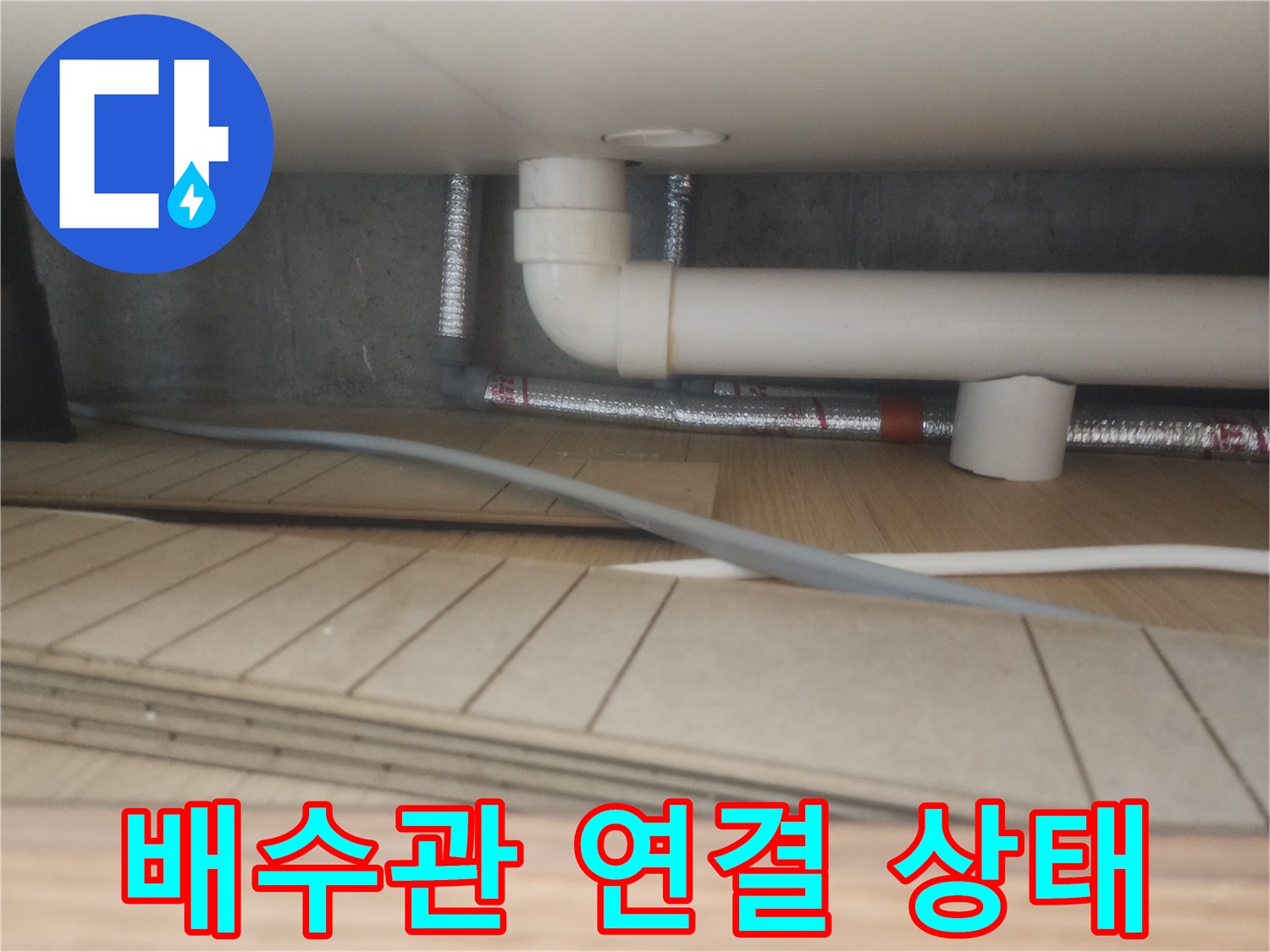 싱크대 하단 흰색 관과 은색 자재의 연결 부위