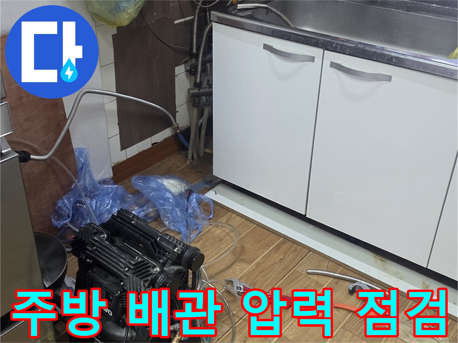 싱크대 하부장 아래에서 진행 중인 배관 공압 테스트 장면입니다.