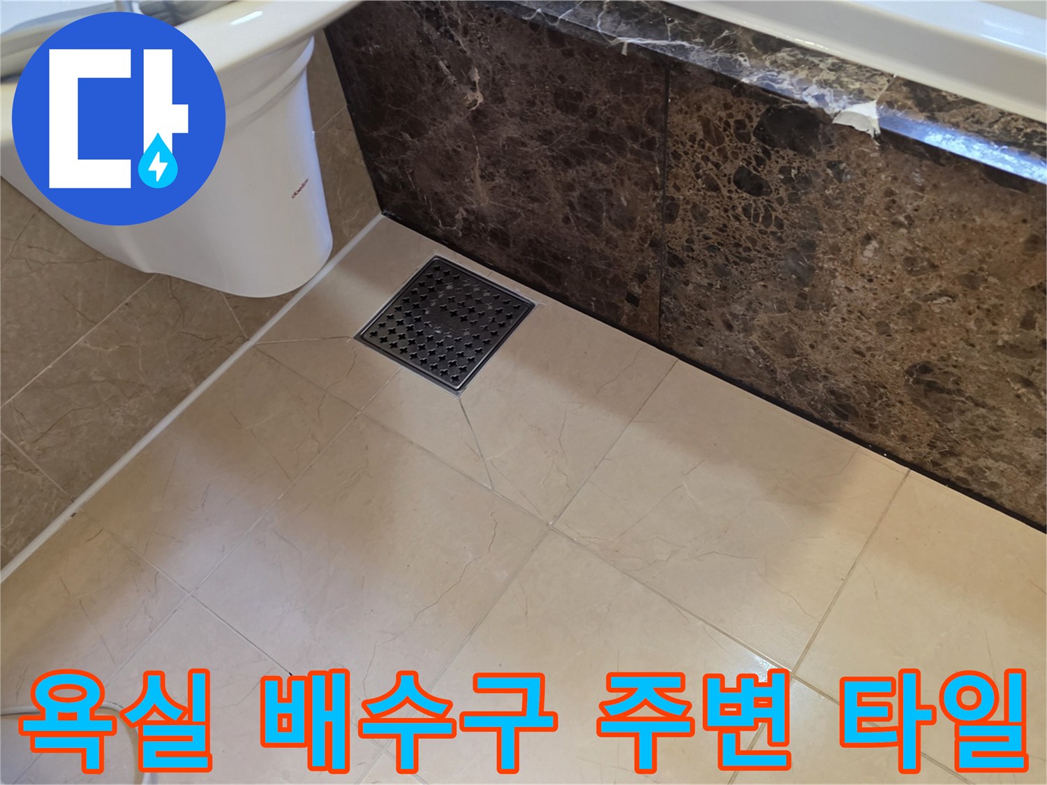 대리석 마감재와 바닥 배수구가 인접한 욕실 내부 모습입니다.